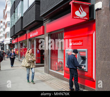 Un homme un retrait d'argent à partir de la direction de Santander sur Tottenham Court Road, Bloomsbury, London, W1, Banque D'Images