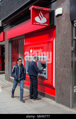 Un homme un retrait d'argent à partir de la direction de Santander sur Tottenham Court Road, Bloomsbury, London, W1, Banque D'Images