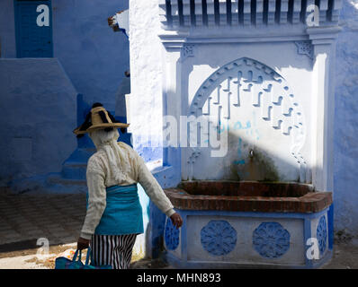 Chefchaouen, Maroc ; femme en habit traditionnel des villages de montagne près de Chefchaouen (Jiblia) à la fontaine publique de la vieille ville. Banque D'Images