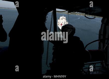 180427-N-MD713-0317TRINCOMOLEE, Sri Lanka (27 avril 2018) Naval Air crewman (hélicoptère) 3e classe Daniel Lewis, affecté à la 'Wildcards' de la mer d'hélicoptères de l'Escadron de Combat (HSC) 23, regarde par la porte d'un MH-60S Sea Hawk que se prépare à atterrir sur la commande de transport maritime militaire navire-hôpital USNS Mercy (T-AH 19) au cours d'un exercice de secours en cas de catastrophe humanitaire et à l'appui de Partenariat du Pacifique 2018 (PP18), le 27 avril 2018. PP18's mission est de travailler ensemble avec l'hôte et les pays partenaires à améliorer l'interopérabilité régionale et de capacités de réaction aux catastrophes, et d'accroître la stabilité. Banque D'Images