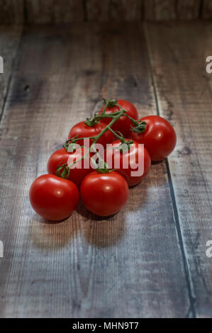 Des tomates mûries sur vigne de table en bois Banque D'Images