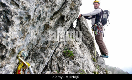 Guide de montagne alpiniste sur le bord d'une voie d'escalade raide à l'approche du prochain lancer Banque D'Images