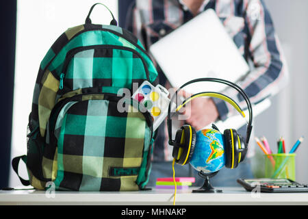 Globe dans les écouteurs et guy avec ordinateur portable en mains Banque D'Images