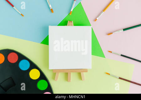 Mise à plat de l'art sur toile avec l'art de chevalet et pinceaux palette sur fond coloré concept créatif minime Banque D'Images