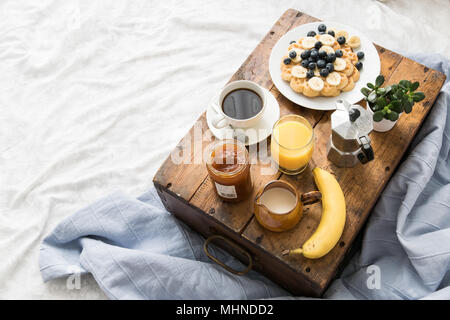Scène de petit-déjeuner confortable au lit avec gaufres sur un week-end ensoleillé Banque D'Images