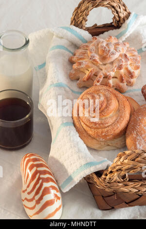 assortiment de pains pour un café du matin fraîchement préparé et du lait sur un linge de table blanc et un panier de fouette. gâteries sucrées pleines d'énergie Banque D'Images