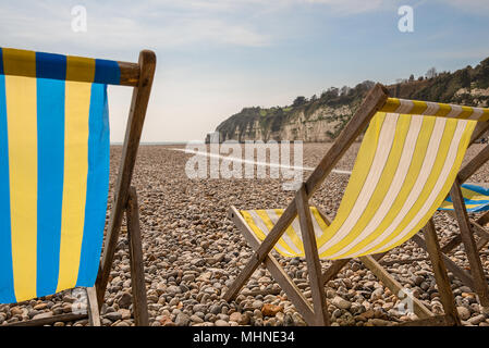 Tradition vide dépouillé et toile encadrée en bois chaises longues sur une plage de galets et de craie en toile de fond, la bière, Devon, UK. Banque D'Images