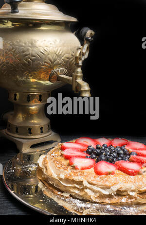 Gâteau de crêpes minces de fraise, de bleuet et de lait concentré dans une plaque de métal et d'un plateau d'un vieil or samovar sur l'arrière-plan. close-up Banque D'Images