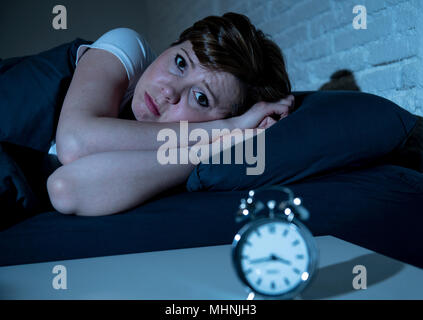 Les jeunes aux cheveux rouge attrayante caucasian woman au lit tard dans la nuit à essayer de dormir souffrant d'insomnie, cauchemars ou troubles du sommeil. Banque D'Images