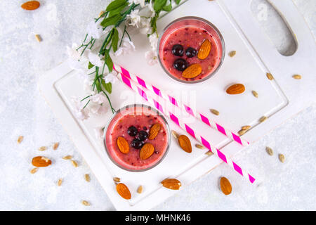 Des smoothies de fruits des bleuets, bananes et amandes dans des verres à cocktail avec tubes sur une planche de bois blanc Banque D'Images