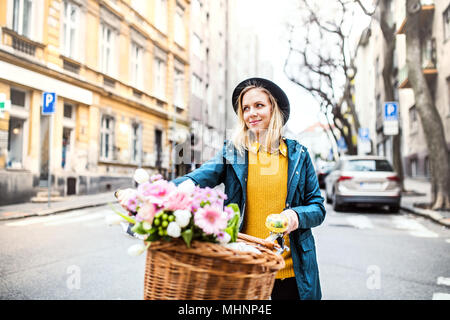 Jeune femme avec location et de fleurs sous le soleil de printemps la ville. Banque D'Images