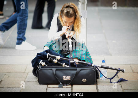 Glasgow en Ecosse, jolie dame femelle busker cornemuse tartan traditionnel en fonction de la configuration de Buchanan Street Banque D'Images