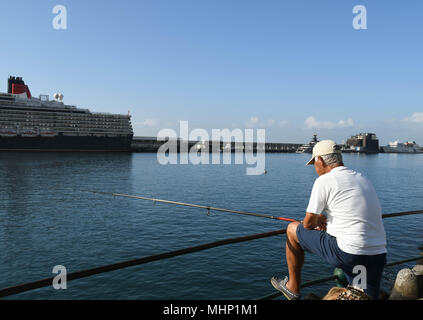 La pêche au large de la personne du côté du port de Funchal, Madère. Le bateau de croisière Queen Elizabeth est dans l'arrière-plan Banque D'Images