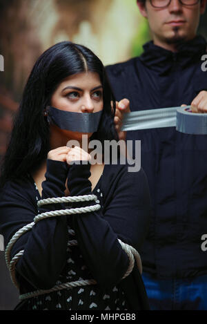 Close up of a mans couvrant une bouche de femme avec ruban, corde attaché avec ses mains. Concept de violence domestique ou d'enlèvement Banque D'Images