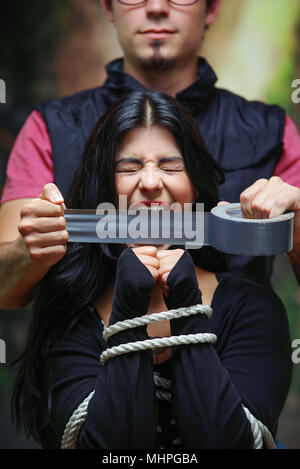 Close up of a mans couvrant une bouche de femme avec ruban, corde attaché avec ses mains. Concept de violence domestique ou d'enlèvement Banque D'Images