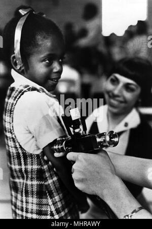 L'agent de santé publique La vaccination d'une jeune fille, avec un jet injecteur, 1986. Image courtoisie Centres for Disease Control (CDC). () Banque D'Images