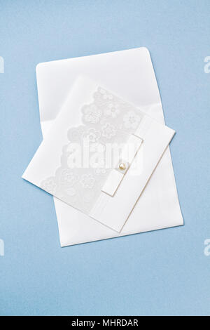 Invitation de mariage blanc avec des fleurs et de l'illustration de la dentelle ruban blanc sur fond de papier bleu clair. Tir vertical. Mignon et beau éléments. Banque D'Images