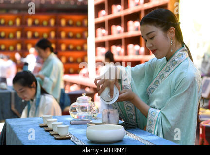 (180503) -- BEIJING, 3 mai 2018 (Xinhua) -- une jeune fille montre l'art du thé de décisions au cours d'une cérémonie traditionnelle du thé préservation à Xiangjie dans Temple Badachu Park à Beijing, capitale de Chine, le 3 mai 2018. La cérémonie du thé préservation fait partie de la culture du thé Chinois. Lors de ces cérémonies, les feuilles de thé sont mis dans des urnes de poterie avant qu'ils sont scellés en vue de leur préservation. (Xinhua/Li) Jundong (LMM) Banque D'Images