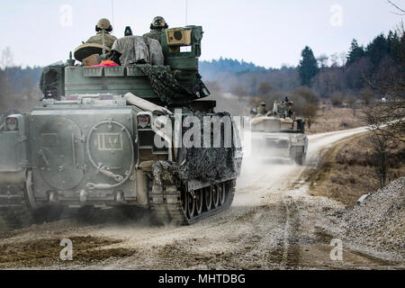 Un véhicule de combat Bradley M2 pistes a M1 Abrams tank, tous deux de la 5e Escadron, 4e régiment de cavalerie blindée, 2e Brigade Combat Team, 1re Division d'infanterie, tout en se déplaçant pour sécuriser une zone au cours d'un exercice de tir réel interarmes (CALFEX) au secteur d'entraînement Grafenwoehr, Allemagne, Mar 26, 2018. (U.S. Army Banque D'Images