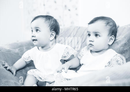 Deux adorables jumeaux bébé assis dans le fauteuil. Banque D'Images