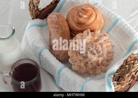 assortiment de pains pour un café du matin fraîchement préparé et du lait sur un linge de table blanc et un panier de fouette. gâteries sucrées pleines d'énergie Banque D'Images