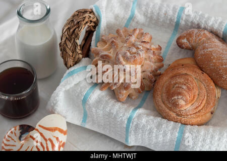 assortiment de pains pour un café du matin fraîchement préparé et du lait sur un linge de table blanc et un panier de fouette. gâteries sucrées pleines d'énergie Banque D'Images