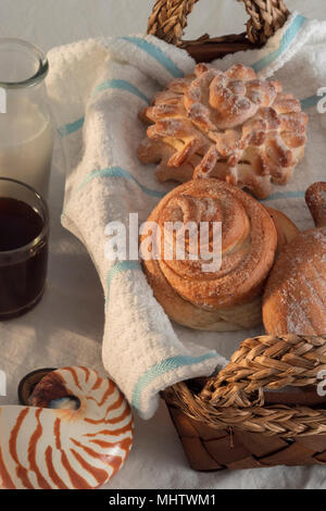 assortiment de pains pour un café du matin fraîchement préparé et du lait sur un linge de table blanc et un panier de fouette. gâteries sucrées pleines d'énergie Banque D'Images