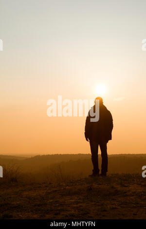 Vue arrière d'une figure masculine en regardant le coucher du soleil, de la montagne Banque D'Images