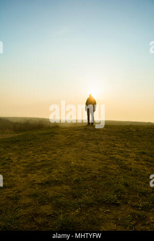 Vue arrière d'une figure masculine debout sur le terrain au coucher du soleil Banque D'Images