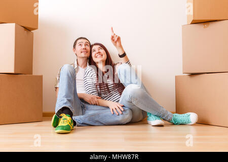 Photo de l'homme et la femme assis sur le plancher entre les boîtes de carton Banque D'Images