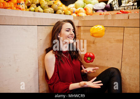 Girl in red peppers jeter sur les fruits store. Banque D'Images