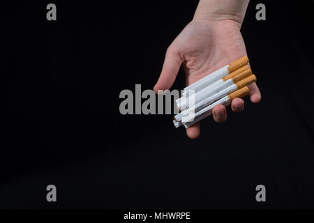 La main est de donner des paquet de cigarettes sur fond noir Banque D'Images