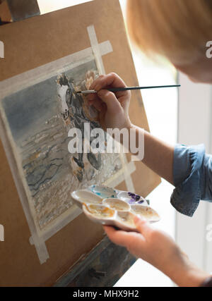 Femme peintre peinture sur une toile avec un pinceau et la tenue d'une palette de couleurs Banque D'Images