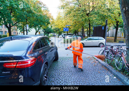 Munich, Allemagne - 16 octobre 2017 : la concierge dans l'uniforme orange supprime le feuillage dans le parc Banque D'Images