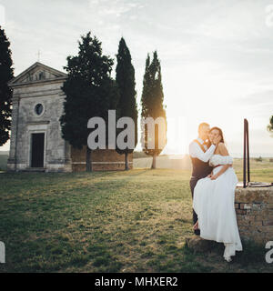 Happy smiling couple élégant la marche et s'embrasser en Toscane, Italie le jour de leur mariage. Banque D'Images