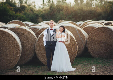 Jeune couple dans l'amour en plein air en Toscane debout sur hay bale Banque D'Images