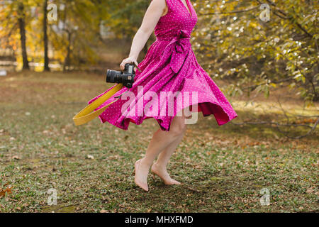 Jeune femme avec caméra dancing in park, du cou vers le bas Banque D'Images