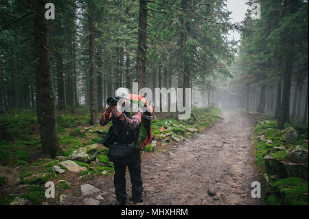 L'homme avec l'appareil photo en montagne hivernale avec sac à dos Banque D'Images