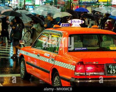 Vie nocturne vibrante Tokyo - taxi colorés attend que les gens traversent la route sur une nuit pluvieuse Banque D'Images