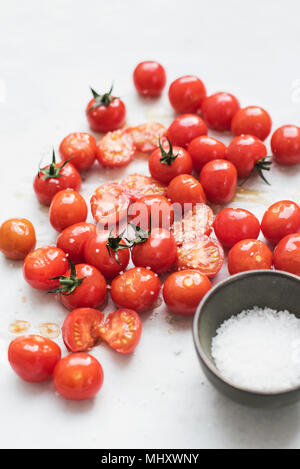 Les tomates cerise avec assaisonnement sur papier cuisson Banque D'Images