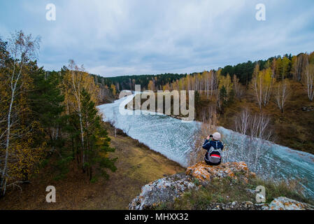 Vue arrière des de jeunes female hiker photographing river à partir de roches, Kislokan, Evenk, Russie Banque D'Images