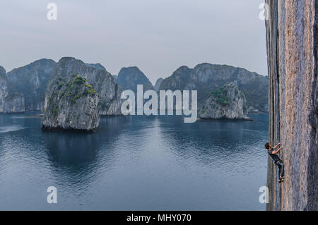 L'homme l'escalade sur roche calcaire, Ha Long Bay, Vietnam Banque D'Images