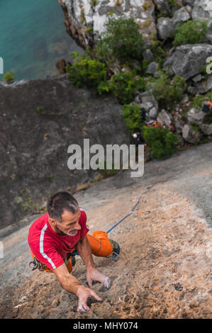 L'homme l'escalade sur roche calcaire, vue de dessus, la baie d'Ha Long, Vietnam Banque D'Images