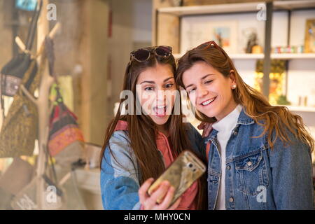 Deux amis dans la boutique, en tenant, using smartphone selfies Banque D'Images