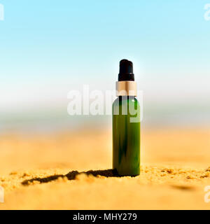 Bouteille de crème solaire dans le sable contre la mer arrière-plan avec copyspace. Locations et voyage d 'papier peint. Concept de soins de la peau. Culture Square Banque D'Images