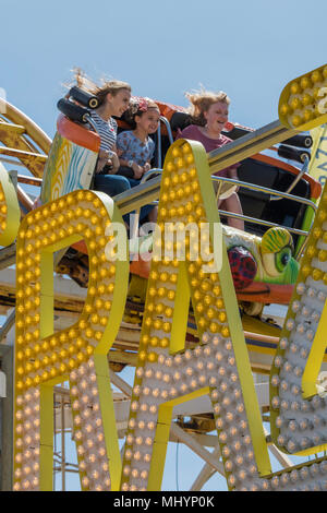 Trois personnes s'amusant sur les montagnes russes sur Palace Pier de Brighton, Brighton, Angleterre, Royaume-Uni. Banque D'Images
