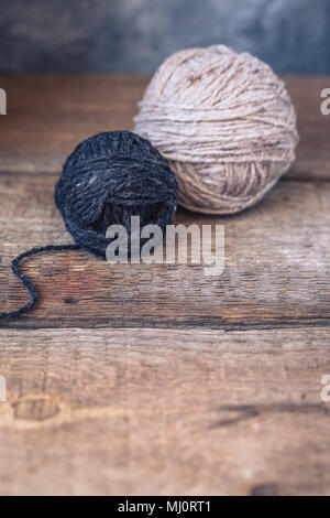 Boules de fils gris et beige sur un fond de bois rustique, tonique Banque D'Images