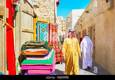 DOHA, QATAR - 13 février 2018 : les hommes du Qatar à pied le long de la rue de Souq Waqif en tenue traditionnelle - keffieh (foulard) et dishdasha ou thobe ( Banque D'Images