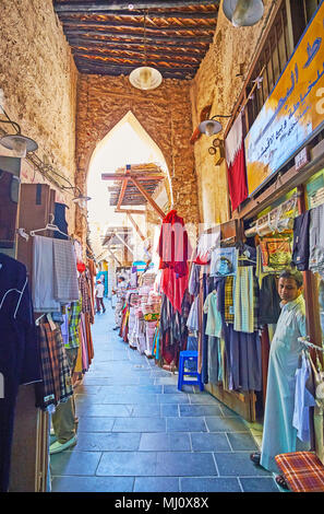 DOHA, QATAR - février 13, 2018 : la ruelle étroite avec les magasins de vêtements masculins traditionnels de Souq Waqif, le 13 février à Doha Banque D'Images