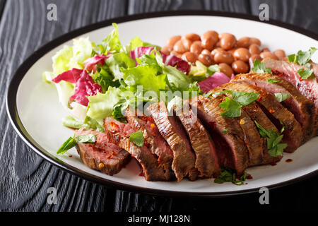 Steak de bœuf haché grillé avec une salade fraîche et de haricots gros plan sur une plaque horizontale. Banque D'Images